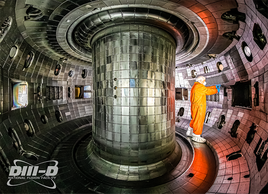  A man in an orange jumpsuit works in a circular space covered in metal tiles with a metal core in the center.