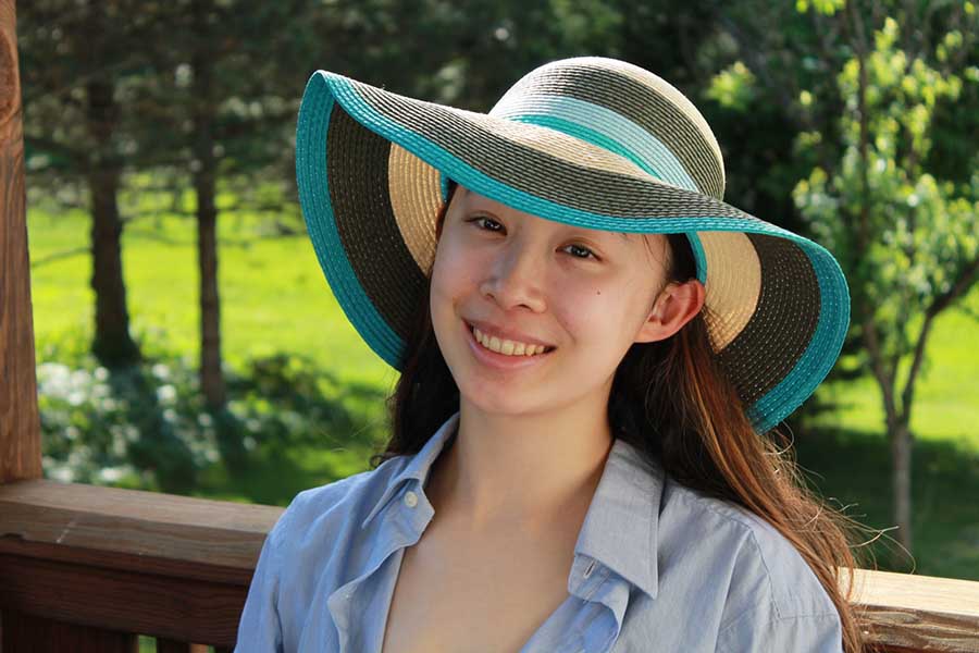  Portrait of Clare Jin in a blue, green and cream floppy hat.