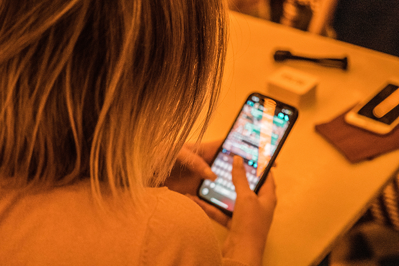  A person with dark hair is seen from the back using a cell phone.