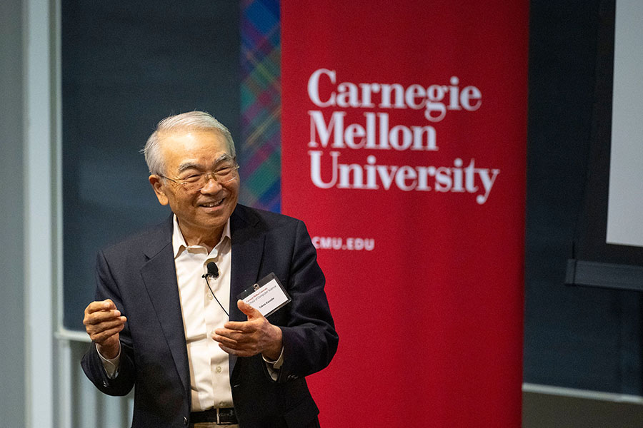 Takeo Kanade stands in front of a Carnegie Mellon University banner.